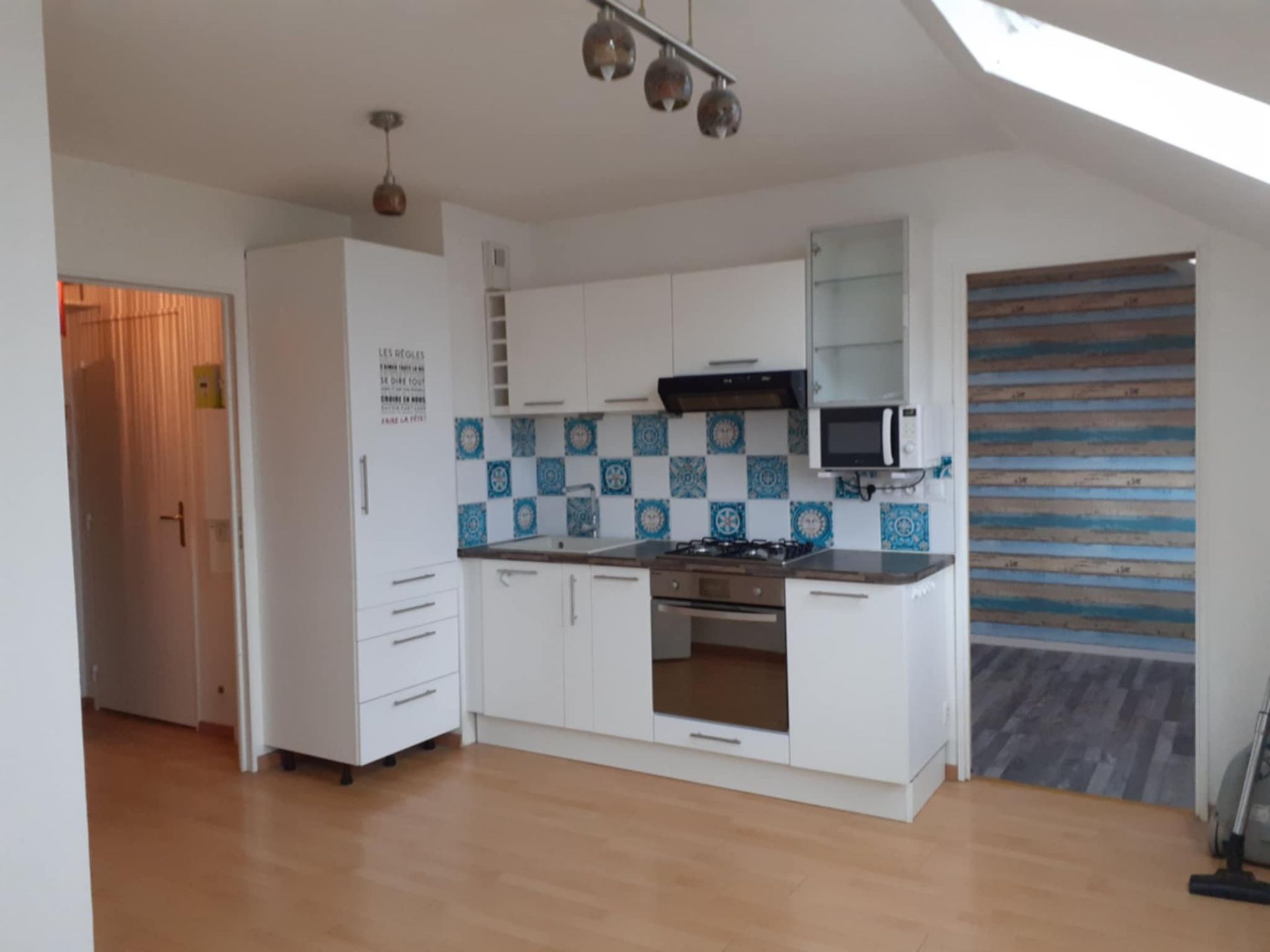 Cuisine avec des meubles blancs et de la crédence bleue