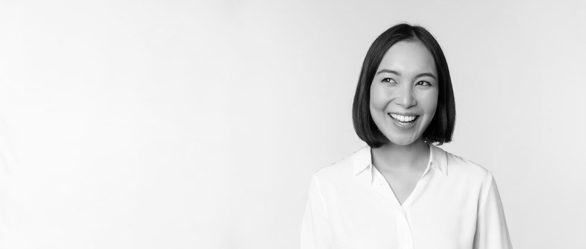 Una fotografía en blanco y negro de una mujer sonriente con una camisa blanca.