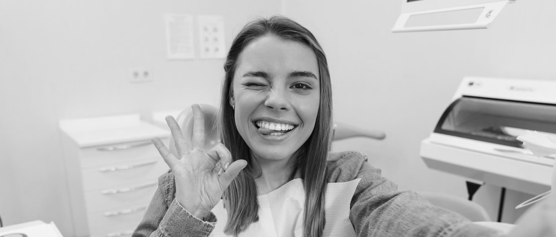 Una mujer se toma una selfie en un consultorio dental y sonríe.