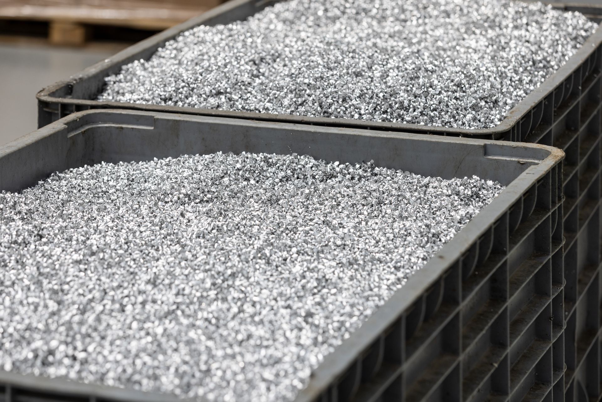 Deux plateaux remplis de granules argentés brillants dans des bacs en plastique noir.