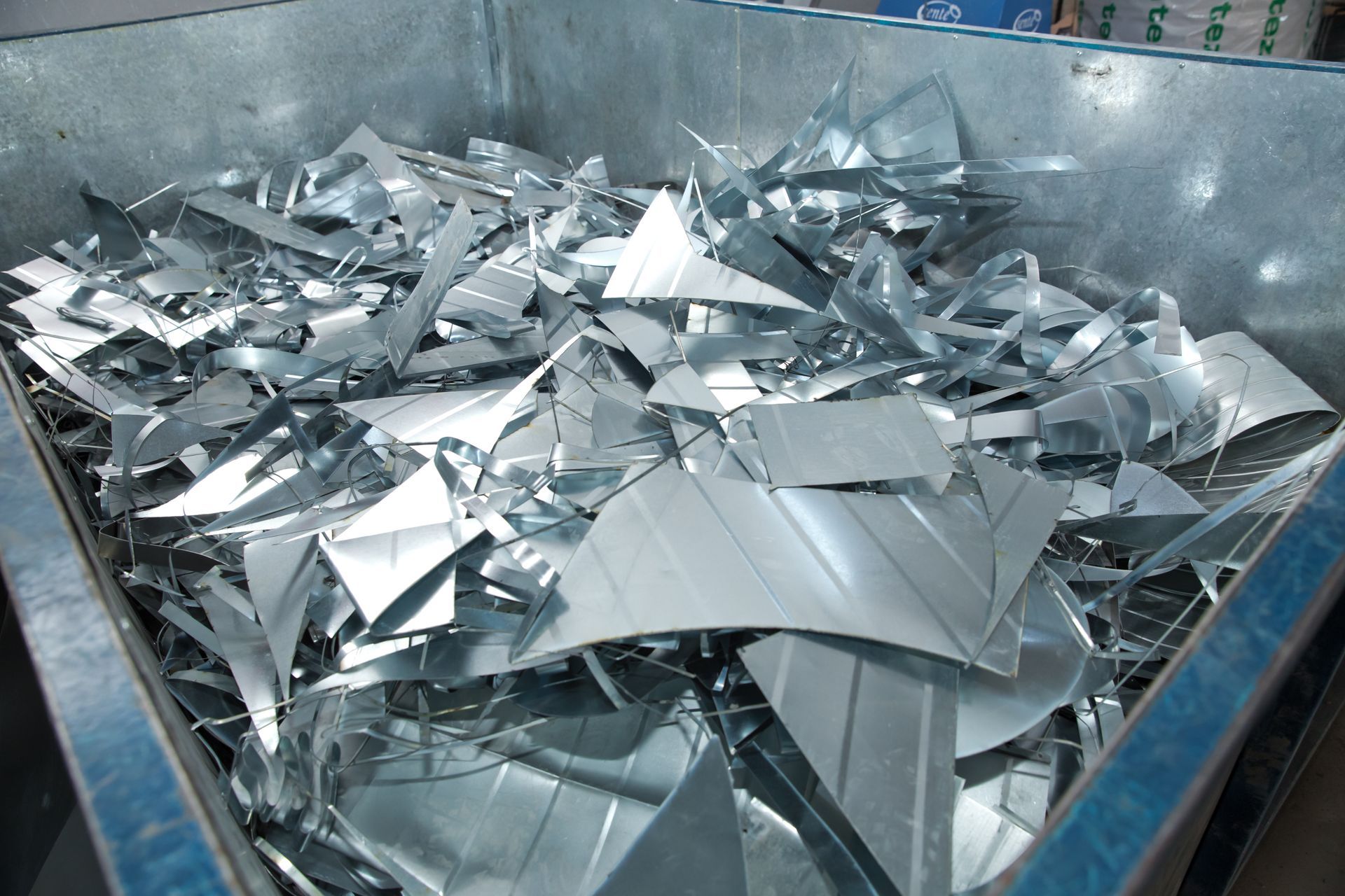 Bac rempli de chutes de métal argenté brillant et de feuilles triangulaires empilées ensemble.
