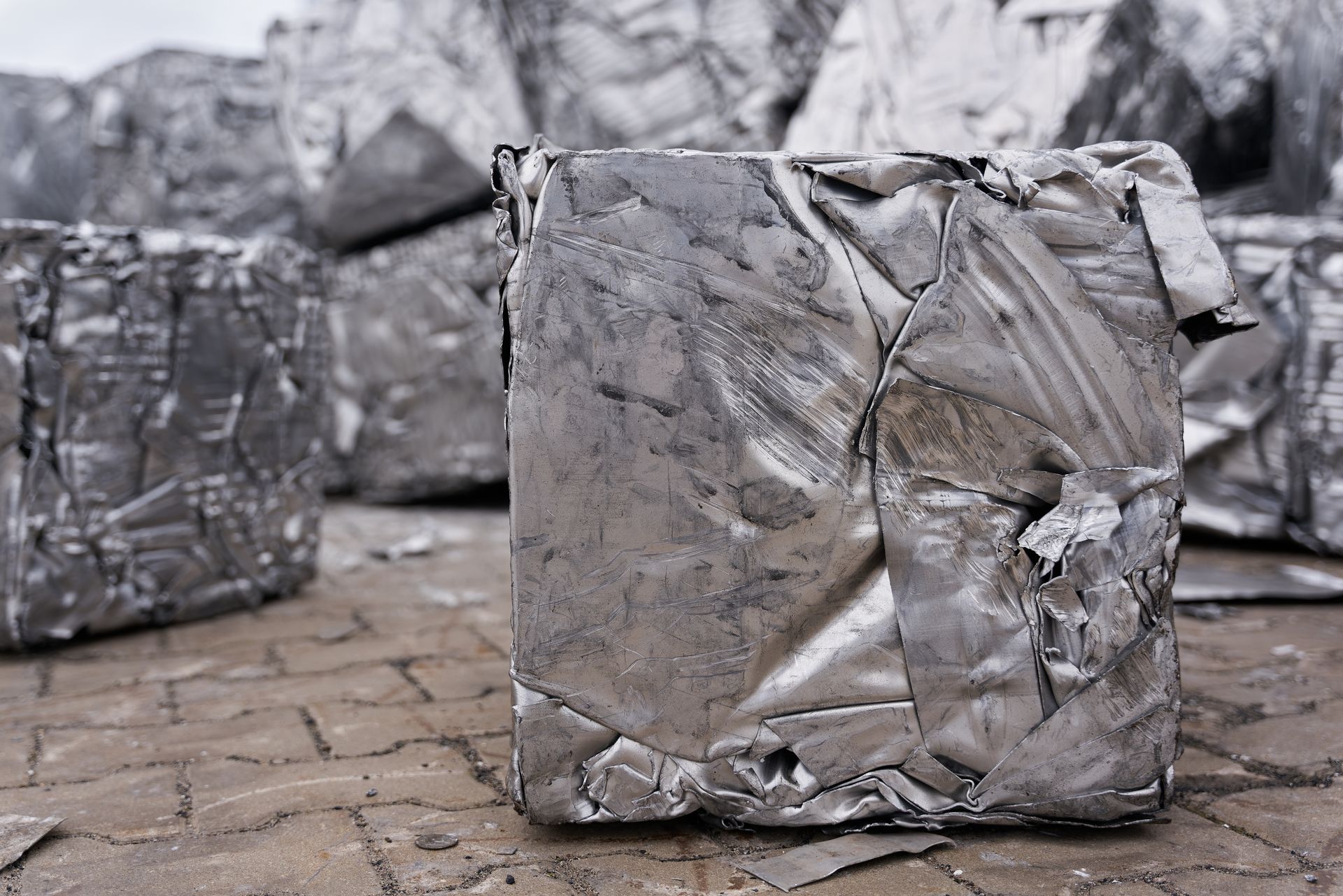 Cubes de métal argenté empilés sur une surface pavée.
