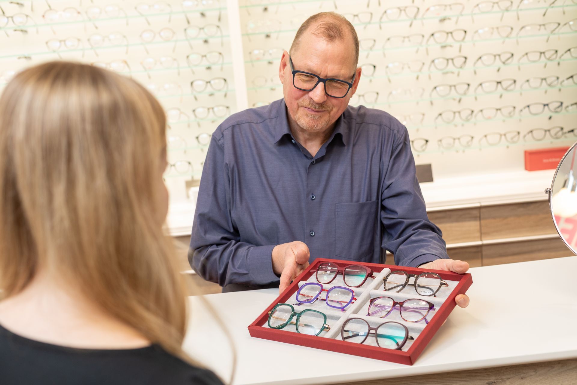 Sonnenbrillen, ausgestellt in Regalen in einem hell erleuchteten Optikergeschäft.