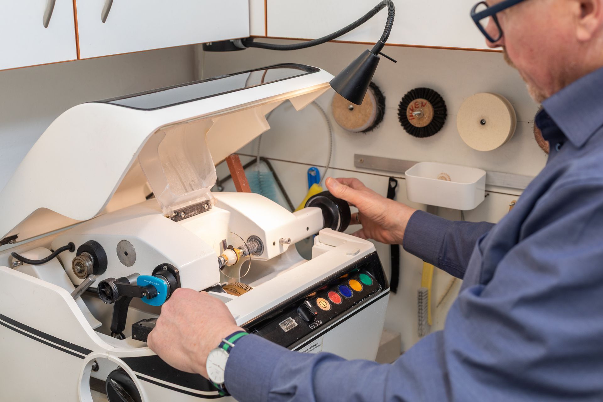 Person reinigt Brille mit einem Mikrofasertuch; Innenaufnahme.