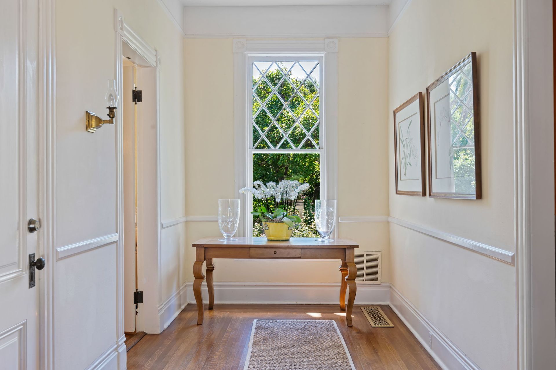 Bright hallway with a table, window, rug, and framed wall art