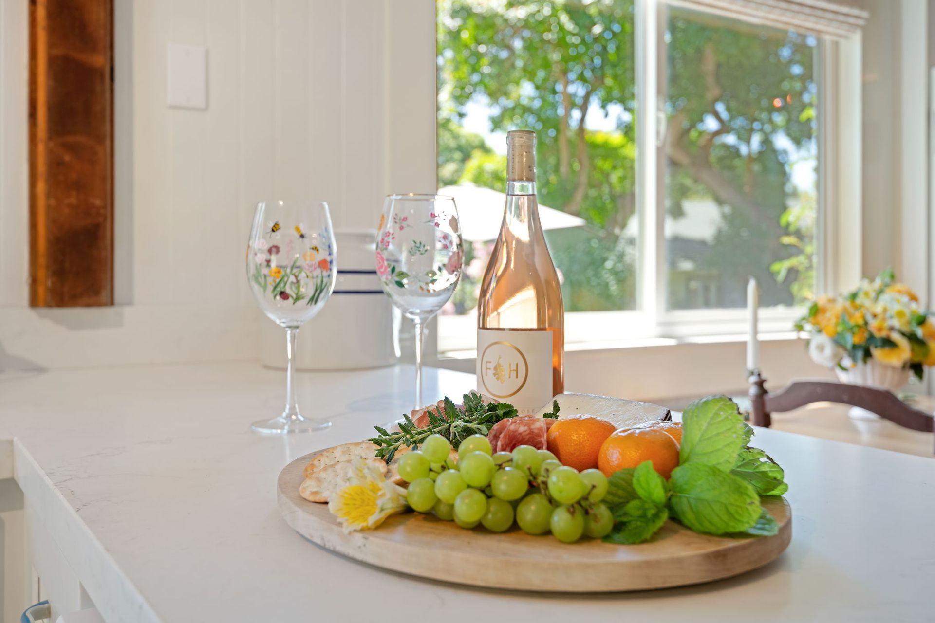 Fruit and wine on a tray beside a bright window in a kitchen