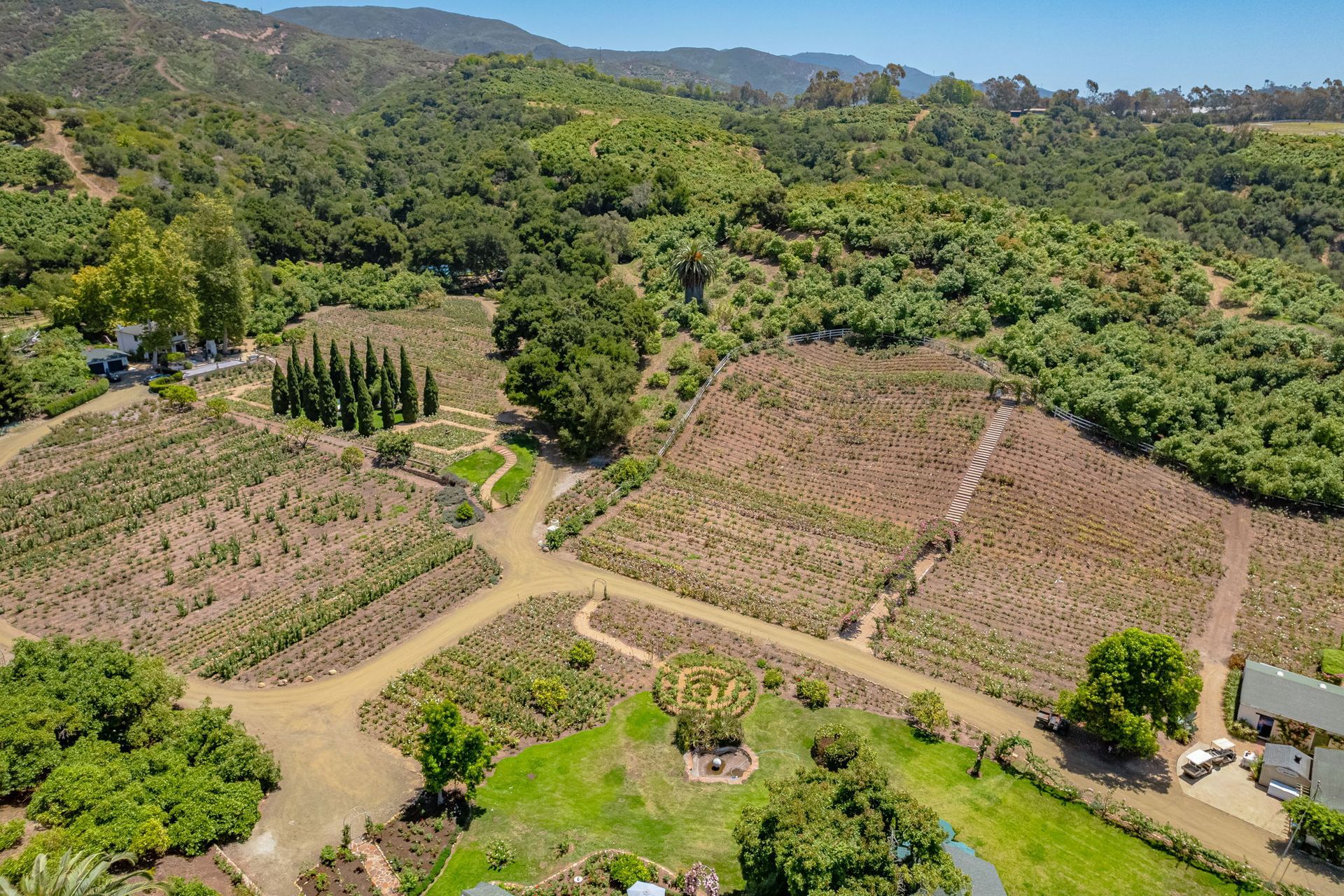 Aerial view of terraced fields, dirt roads, and green hills in a rural valley