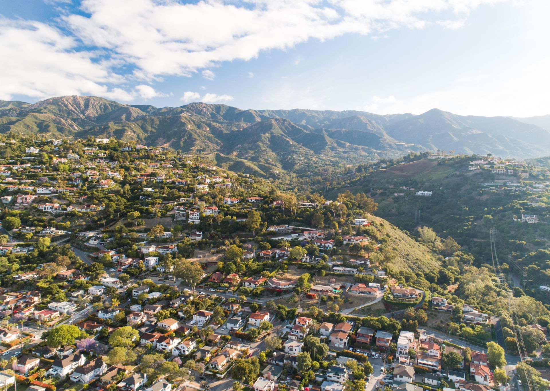 A hillside town with colorful houses nestled among mountains under a bright blue sky.