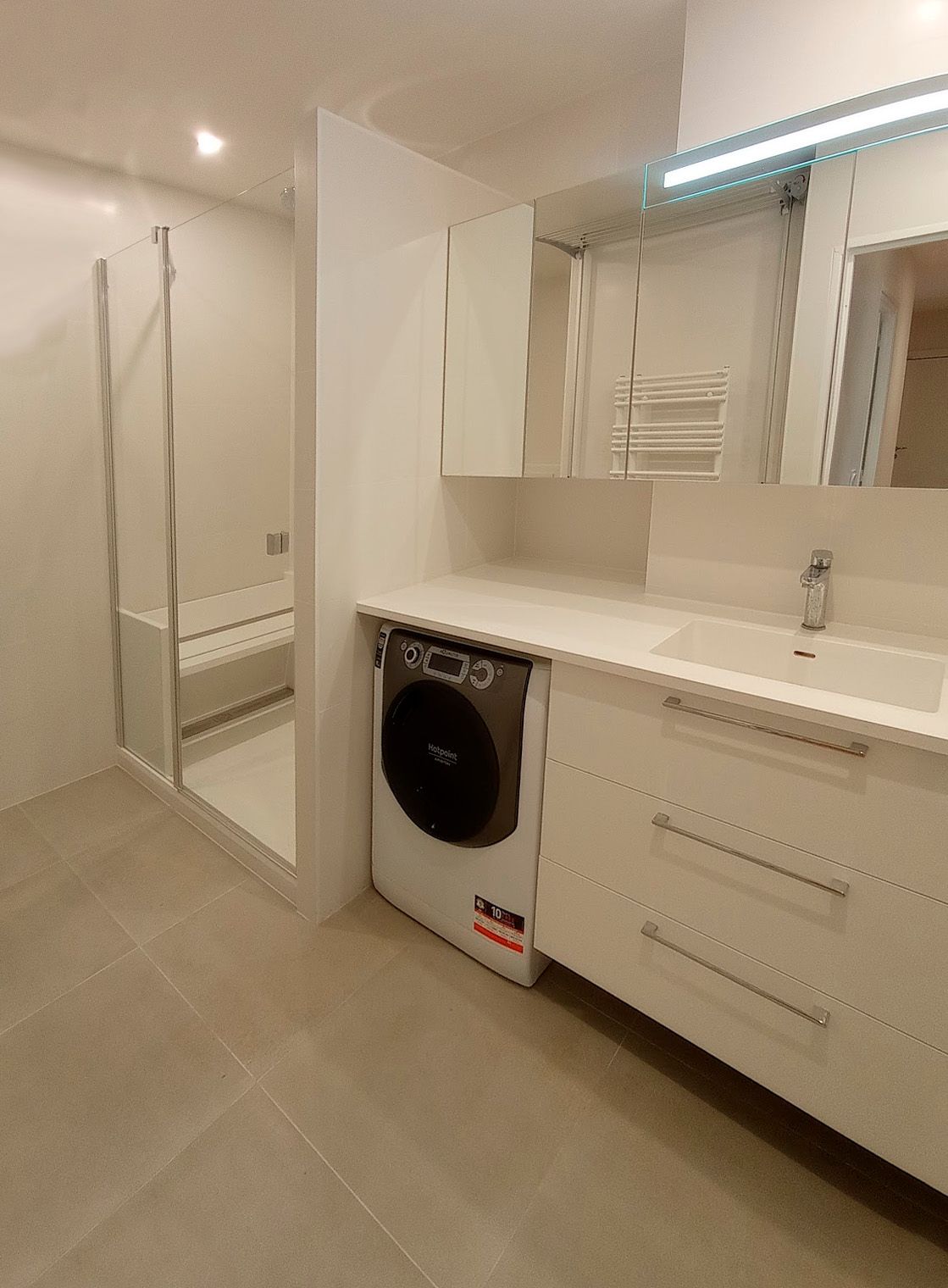 Salle de bains avec meuble, machine à laver et douche