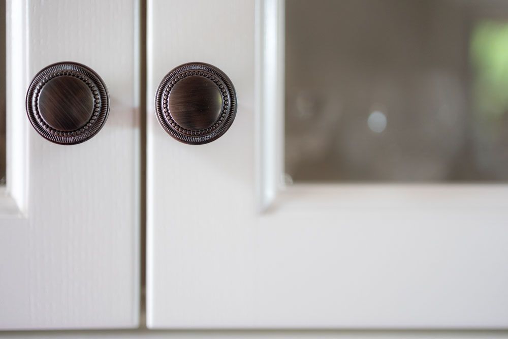 Eine Nahaufnahme von zwei weißen Schranktüren mit braunen Griffen.