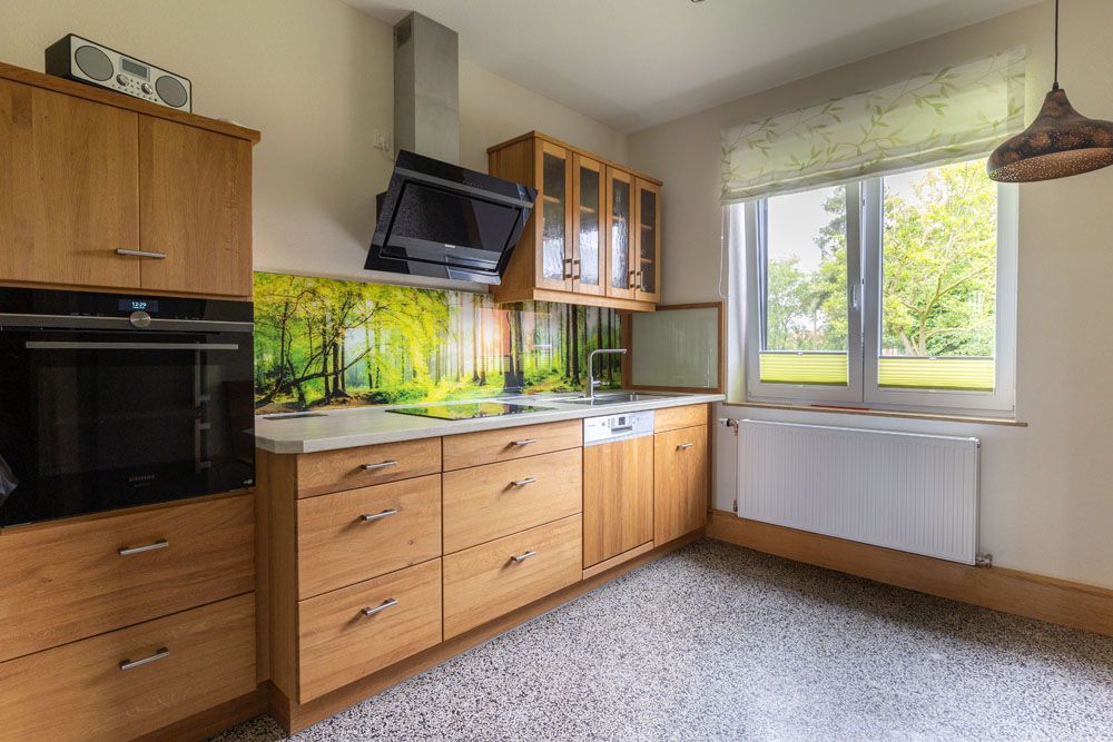 Eine Küche mit Holzschränken, Geräten aus Edelstahl und einem großen Fenster.