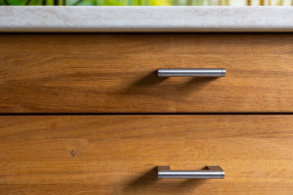 Eine Nahaufnahme von zwei Holzschubladen mit Griffen aus Edelstahl.