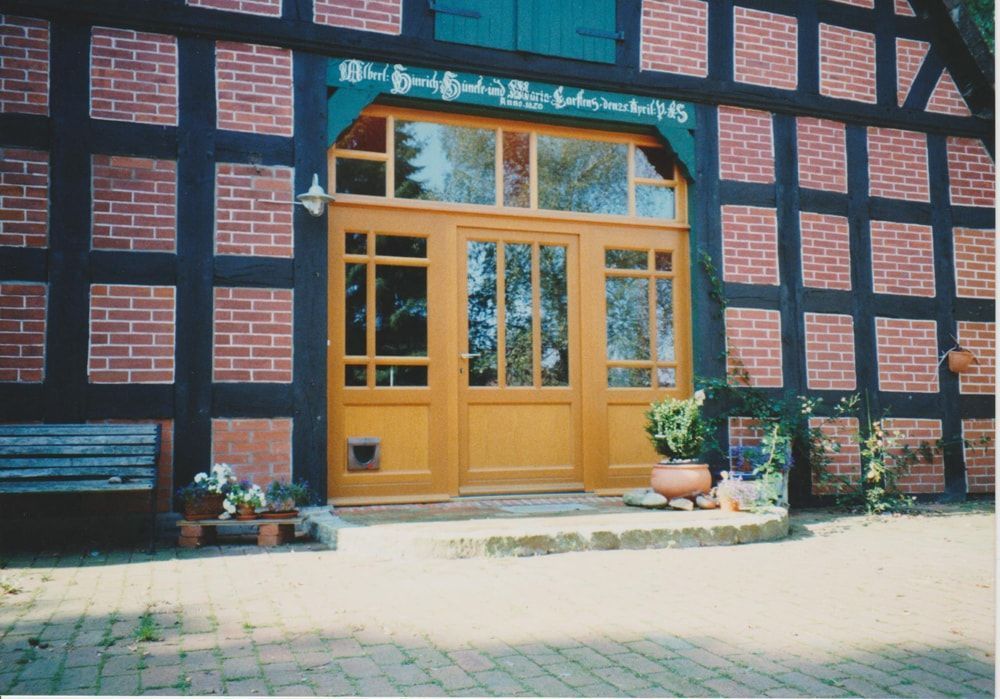 Ein Backsteingebäude mit einer Holztür und einer Bank davor