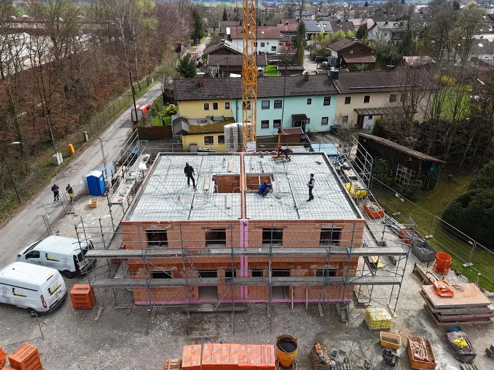 Baustelle mit unfertigem Backsteingebäude, Kran und Arbeitern, aus der Vogelperspektive gesehen