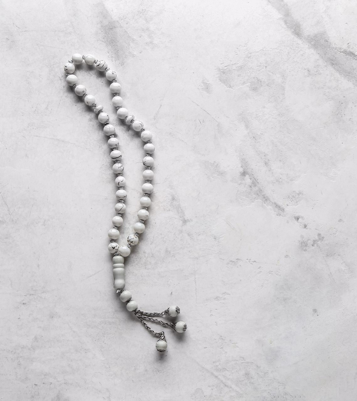 Chapelet blanc sur une surface marbrée.