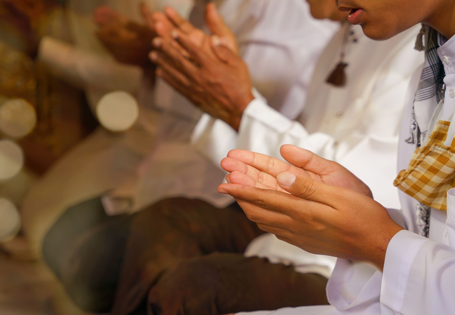 Mains de personnes en tenues blanches en train de prier.