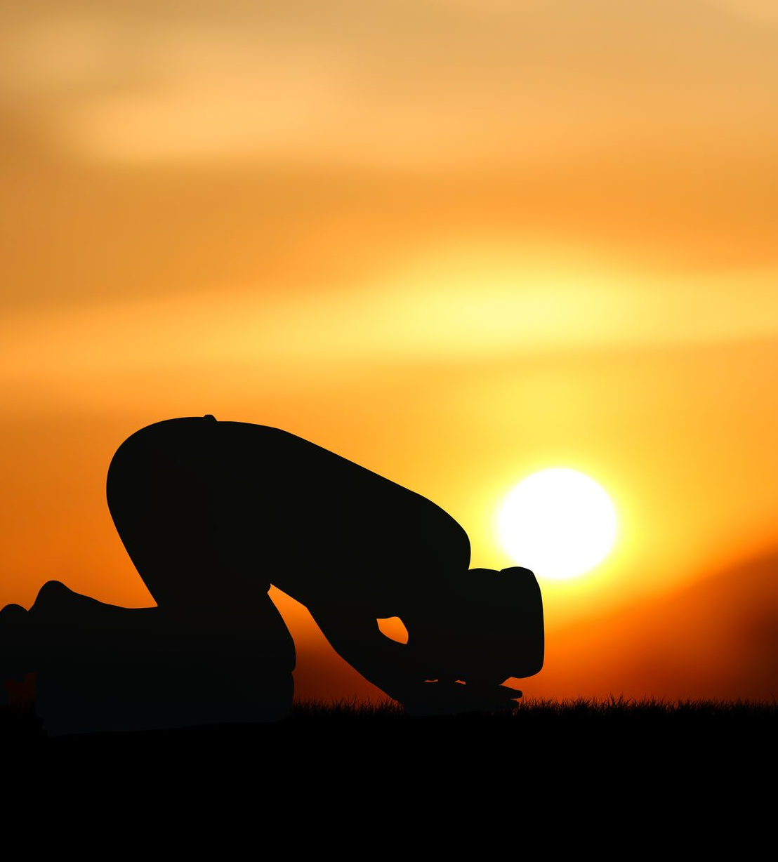 Silhouette d'une personne en prière, agenouillée vers un soleil couchant sur un ciel orange.