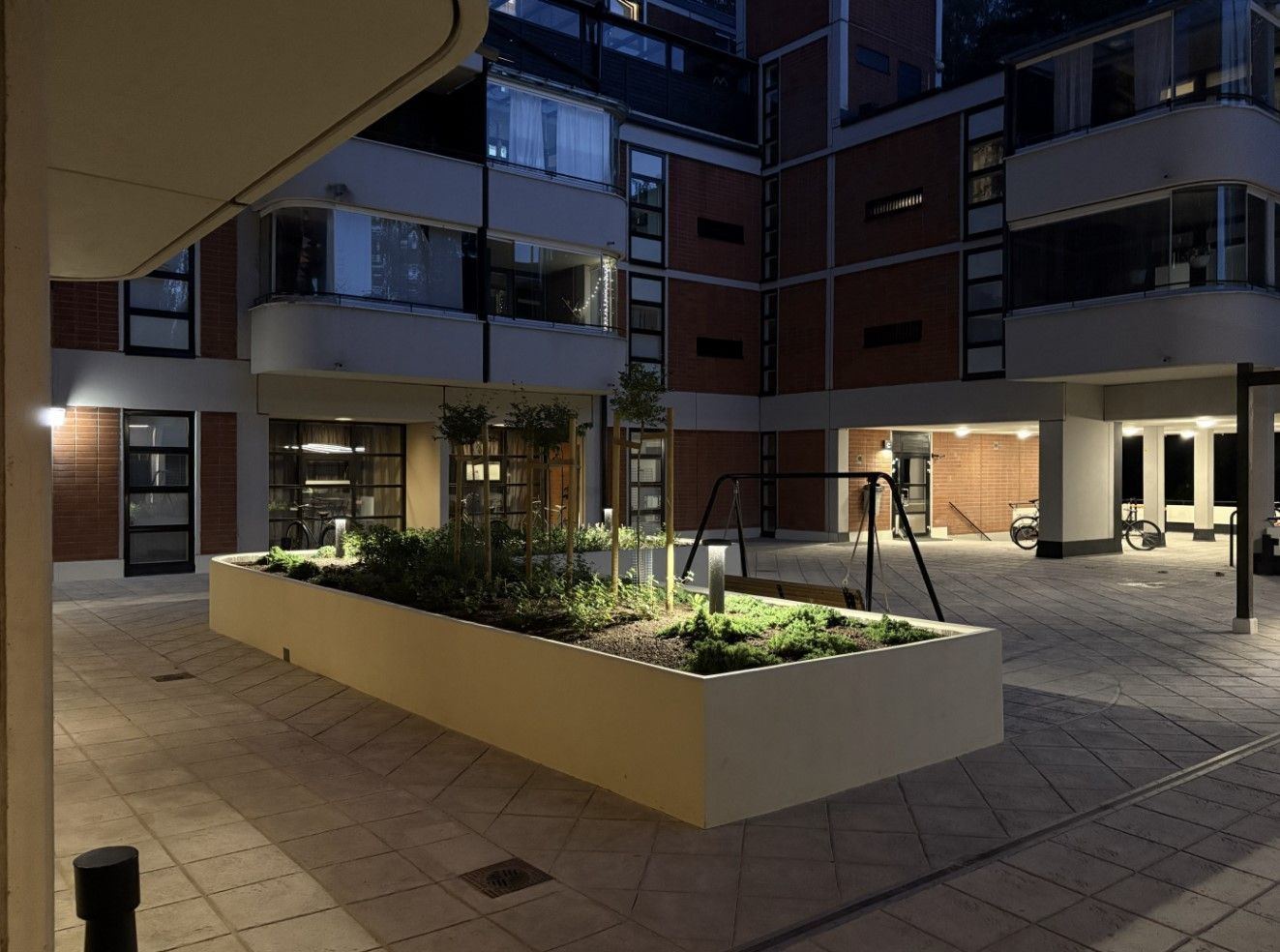 Worker in a hard hat and hi-vis vest inspecting a house foundation with exposed utility pipes.