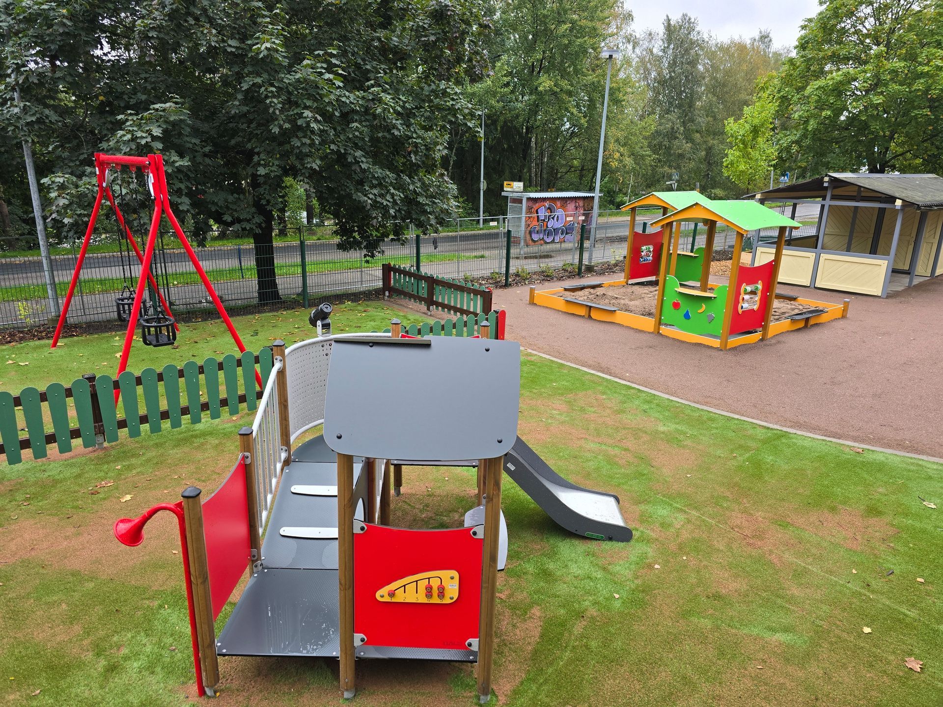 Worker in a hard hat and hi-vis vest inspecting a house foundation with exposed utility pipes.