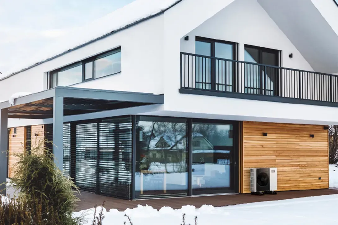 Maison blanche moderne avec murs de verre, éléments en bois et jardin enneigé.