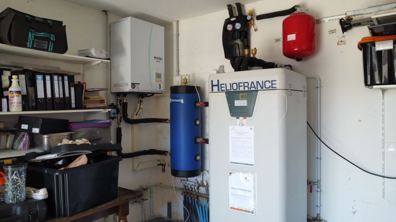 Une pièce abritant les composants du système de chauffage, notamment un chauffe-eau, une chaudière et des réservoirs.