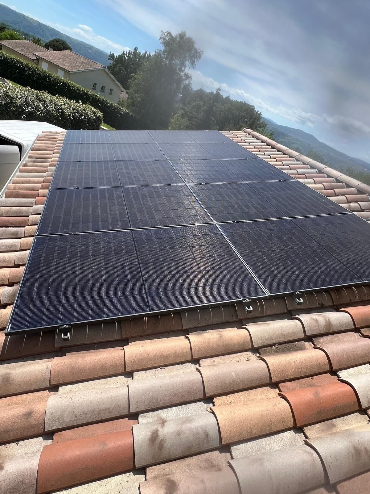 Des panneaux solaires installés sur un toit de tuiles sous un ciel dégagé.