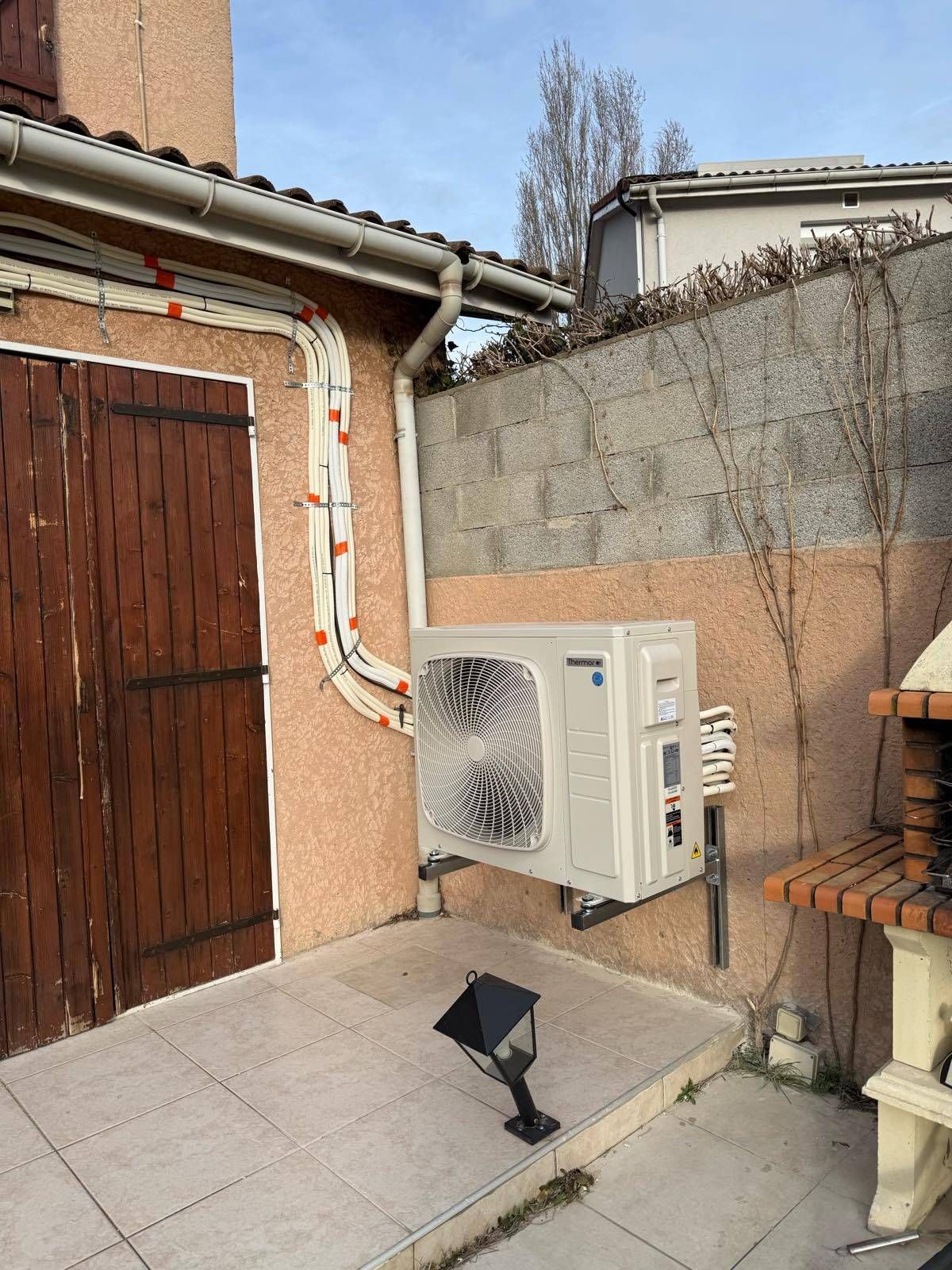 Terrasse extérieure avec climatiseur mural, murs en briques et porte en bois