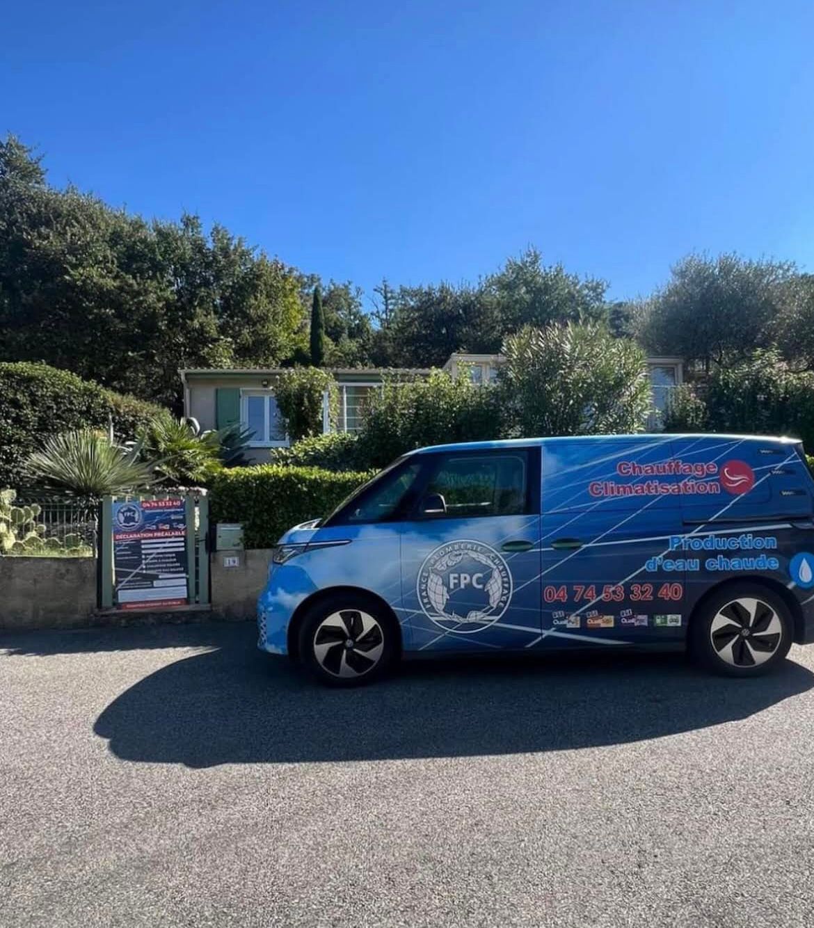 Une camionnette Volkswagen ID. Buzz bleue et blanche avec le logo FPC est garée devant un bâtiment affichant des panneaux de plomberie et de chauffage.