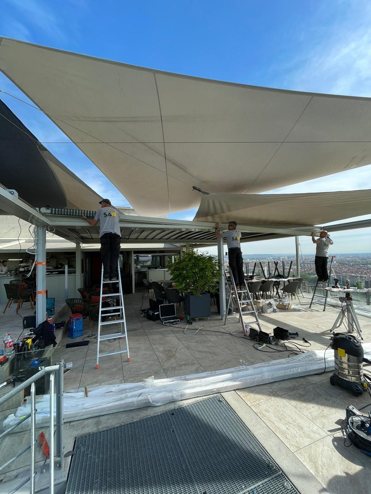 Voiles d'ombrage beiges en cours d'installation