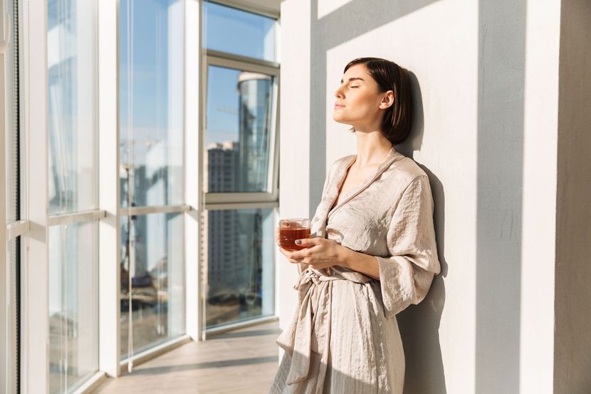 Femme profitant de la lumière offerte par la  pose de grandes fenêtres