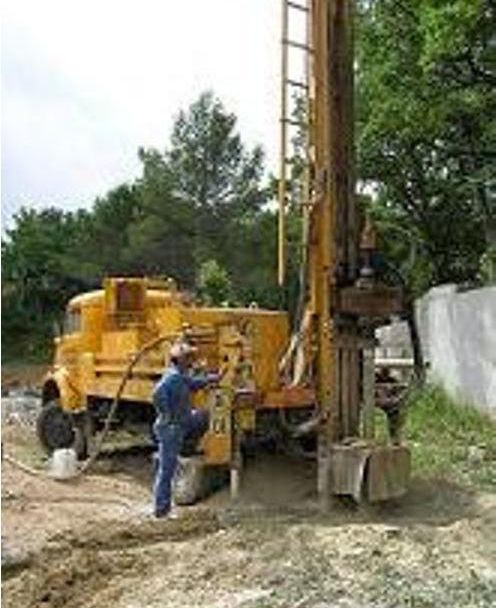 Une foreuse jaune, manœuvrée par un ouvrier à l'extérieur.