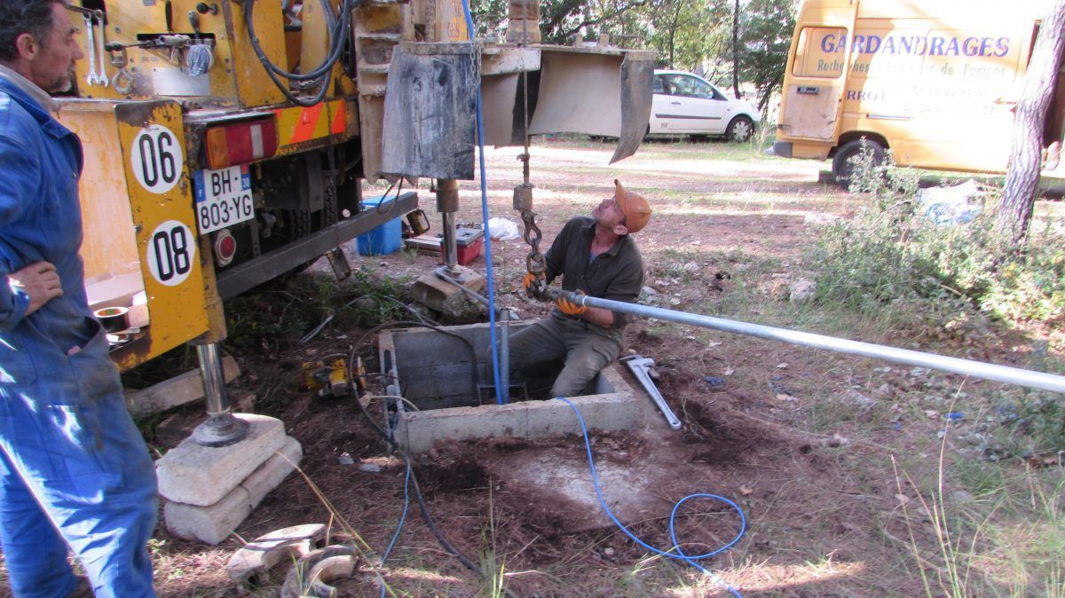 Deux hommes manipulent du matériel de forage sur un chantier de construction.