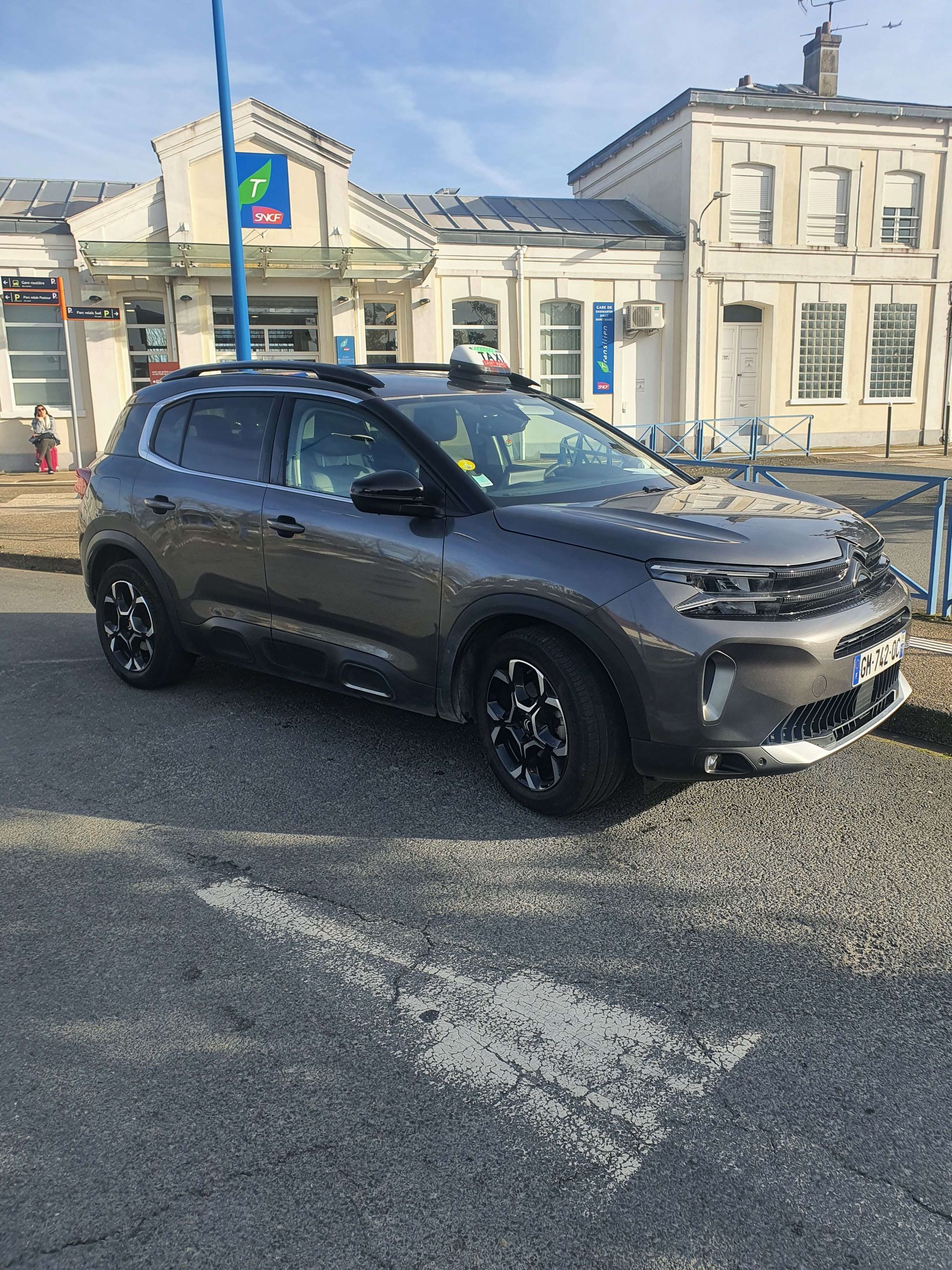SUV gris foncé garé dans une rue devant de vieux bâtiments blancs par une journée ensoleillée