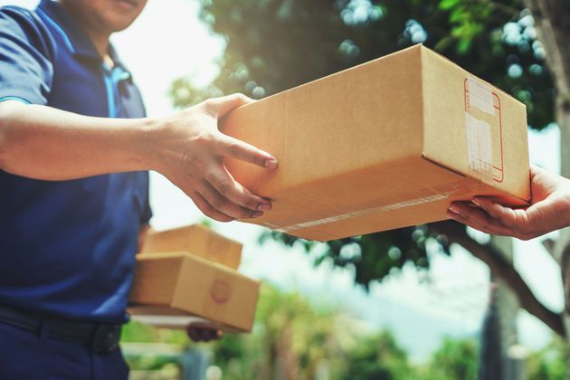 Deux personnes échangeant des cartons à l'extérieur, dans une scène de livraison ensoleillée