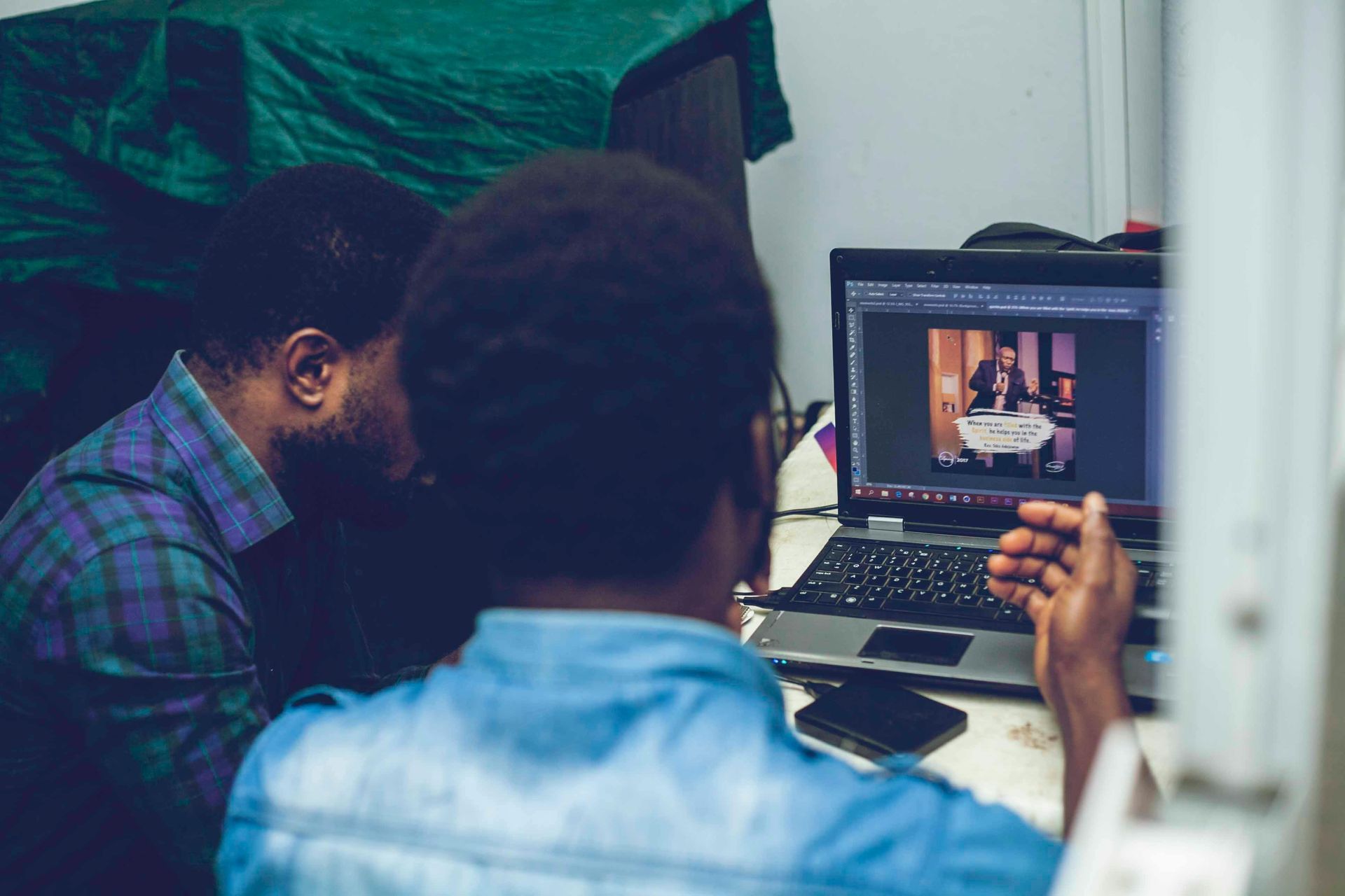 Two men are looking at a laptop computer.