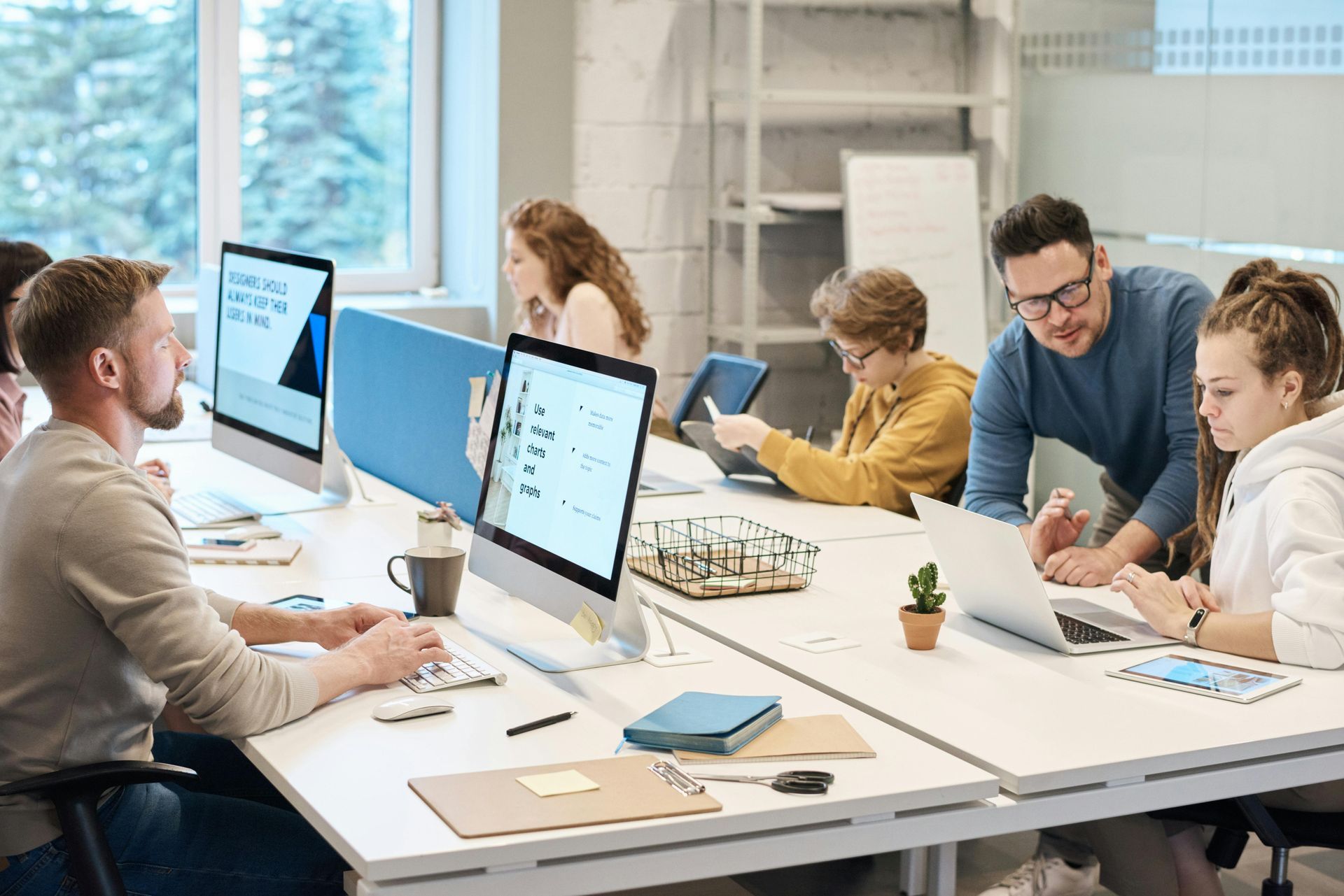 Group of Black women laughing and working on laptops around a conference table.