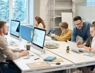 A group of women are sitting around a table with laptops.