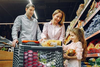 Woman wearing mask shops at a grocery store, near self-checkout with scanner.