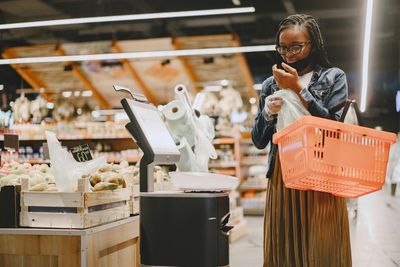 A woman is using a self checkout machine in a grocery store.