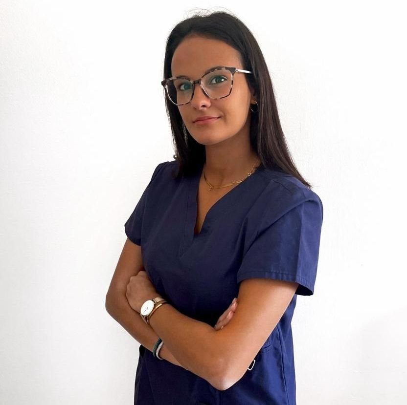 Una mujer que lleva gafas y un reloj está de pie con los brazos cruzados.