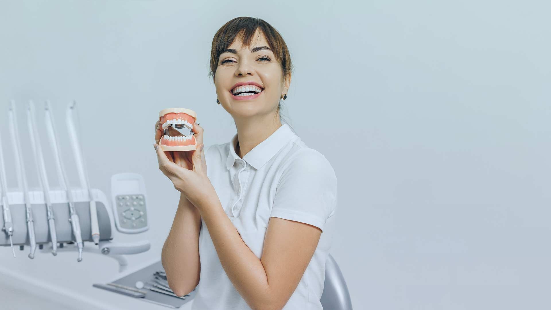 Una dentista sostiene un modelo de los dientes de una persona.
