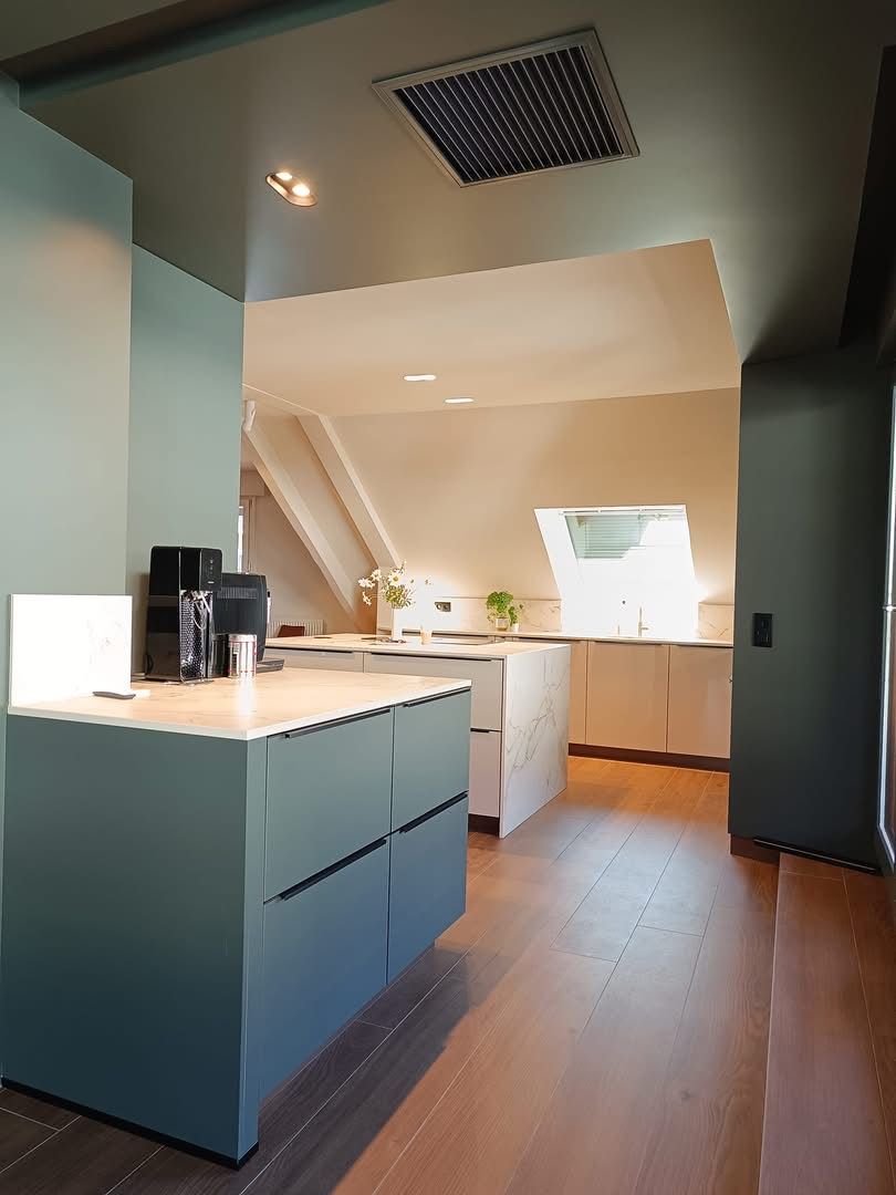 Cuisine moderne avec placards, parquet et îlot central sous une verrière.