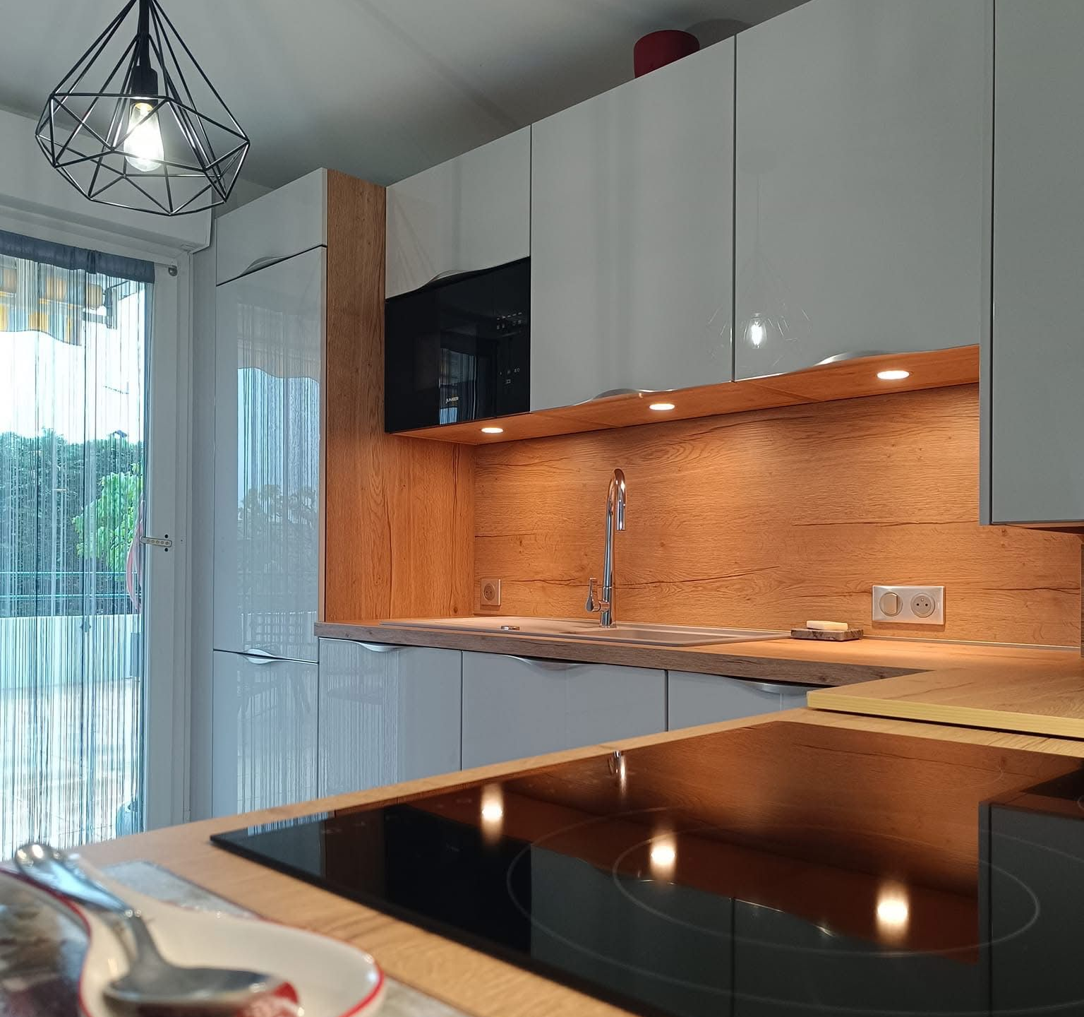 Cuisine moderne avec placards, crédence en bois et plaque de cuisson.