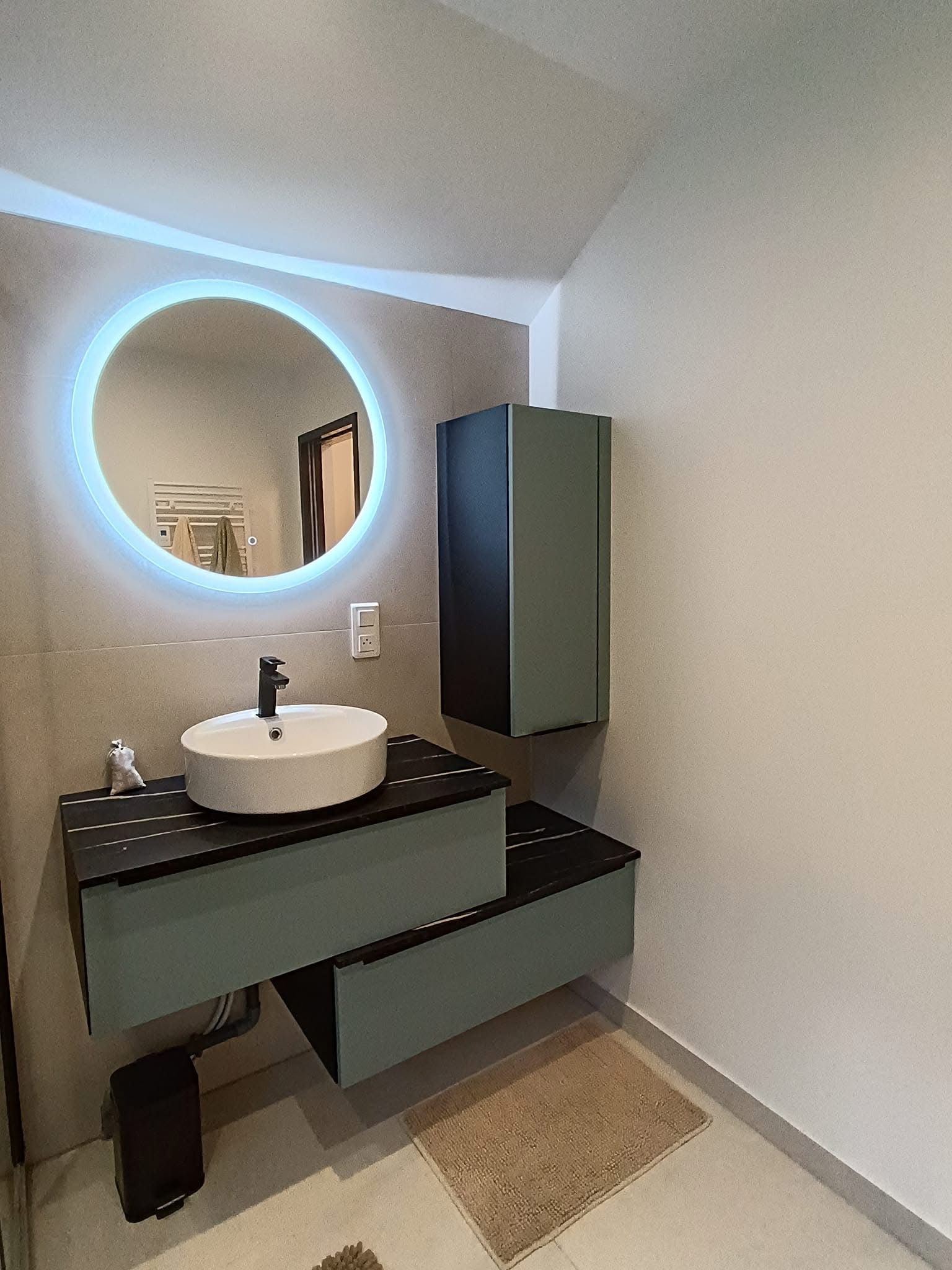 Salle de bains moderne avec miroir rond, lavabo suspendu et meubles.