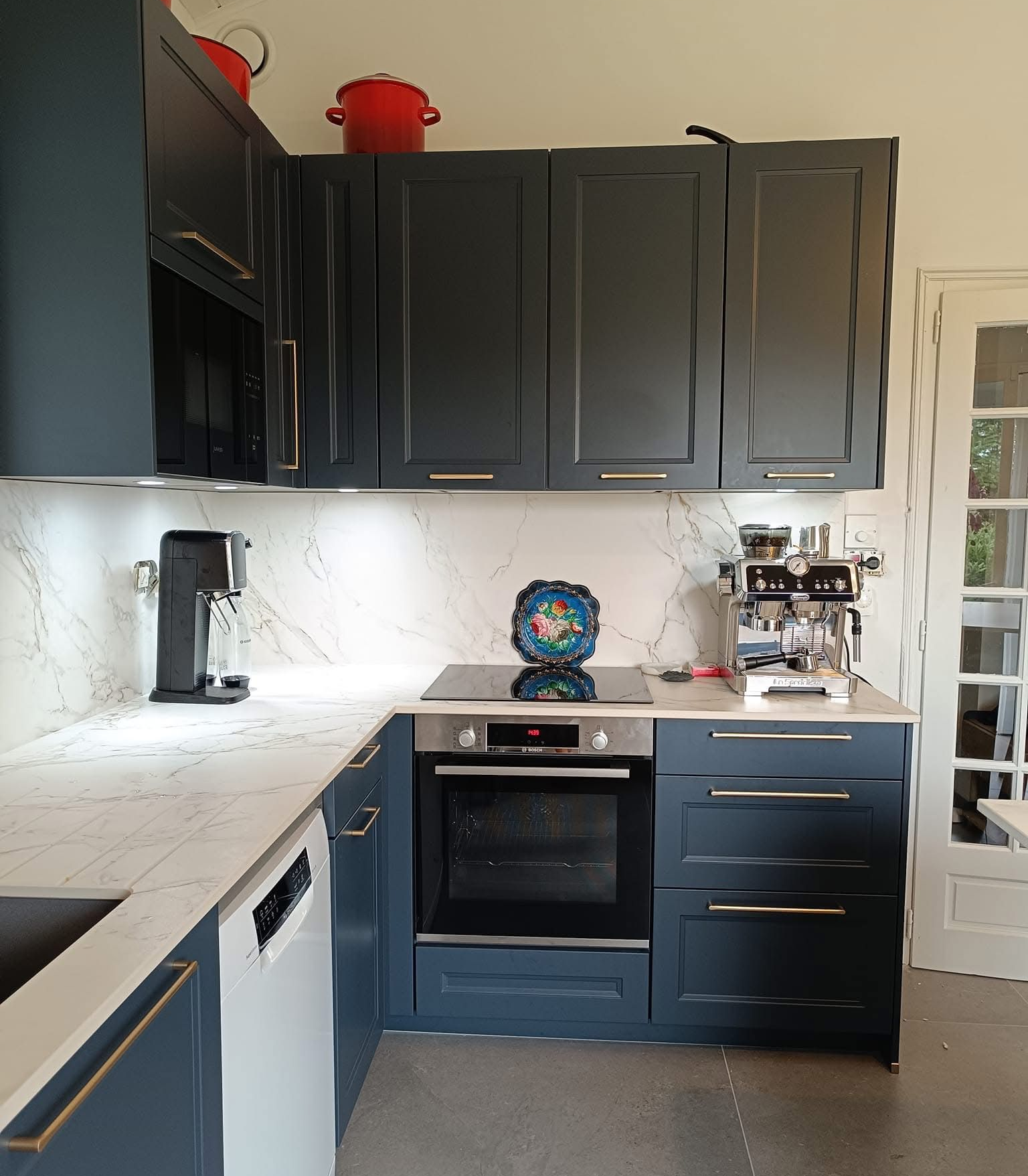 Cuisine avec comptoirs et crédence. Comprend un four, une machine à expresso et des rangements.