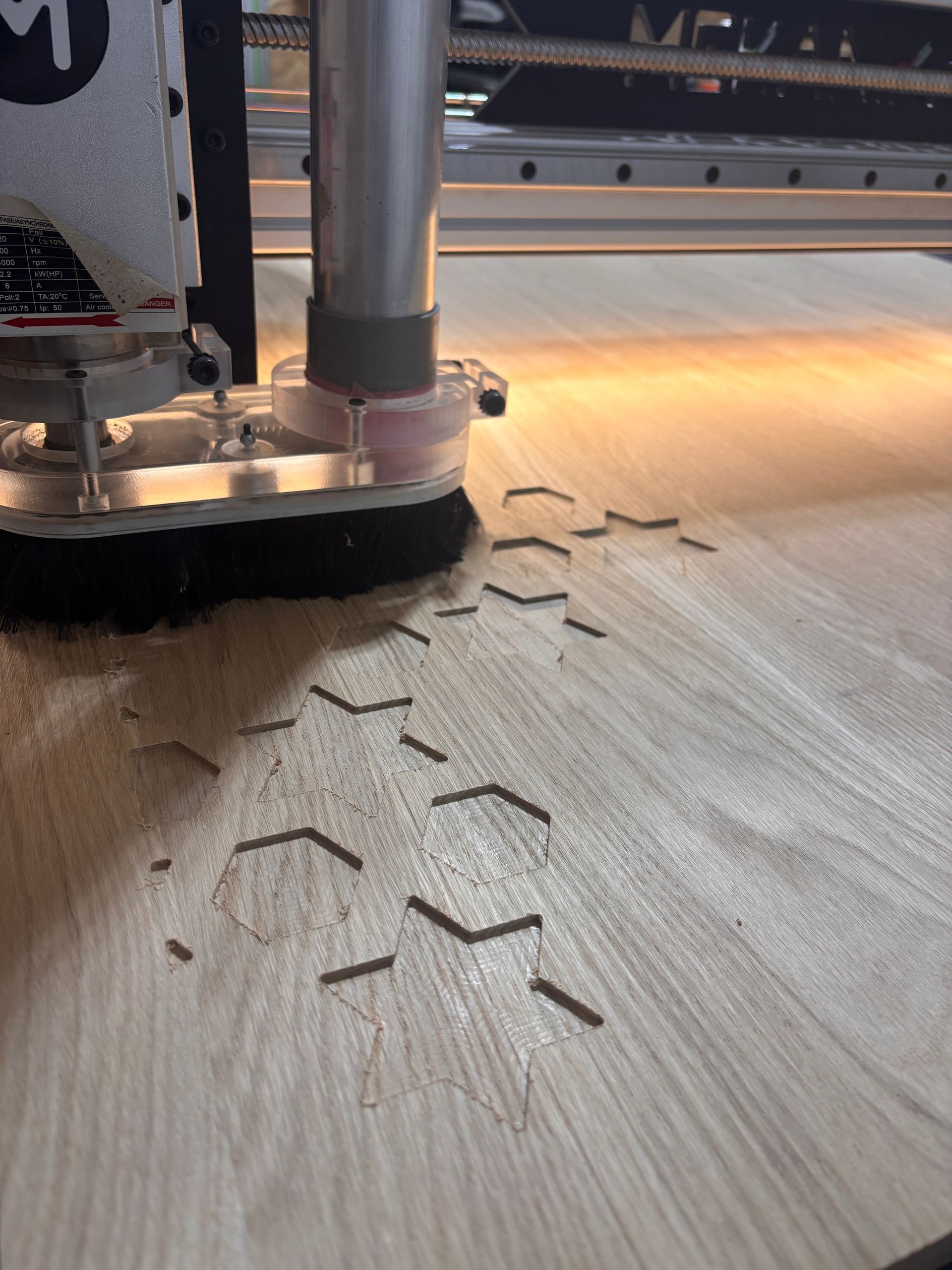 Machine CNC découpant des formes hexagonales dans une surface en bois, en atelier.