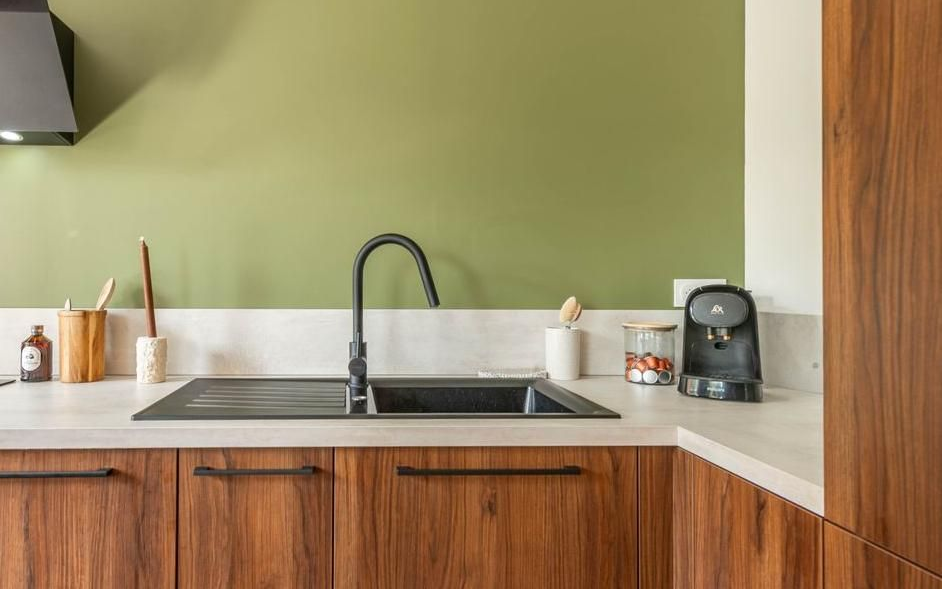 Cuisine avec mur, placards en bois, évier et robinet et cafetière.