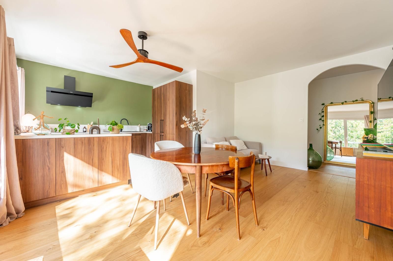 Une cuisine et un salon modernes avec des meubles en bois, un mur et une table à manger.