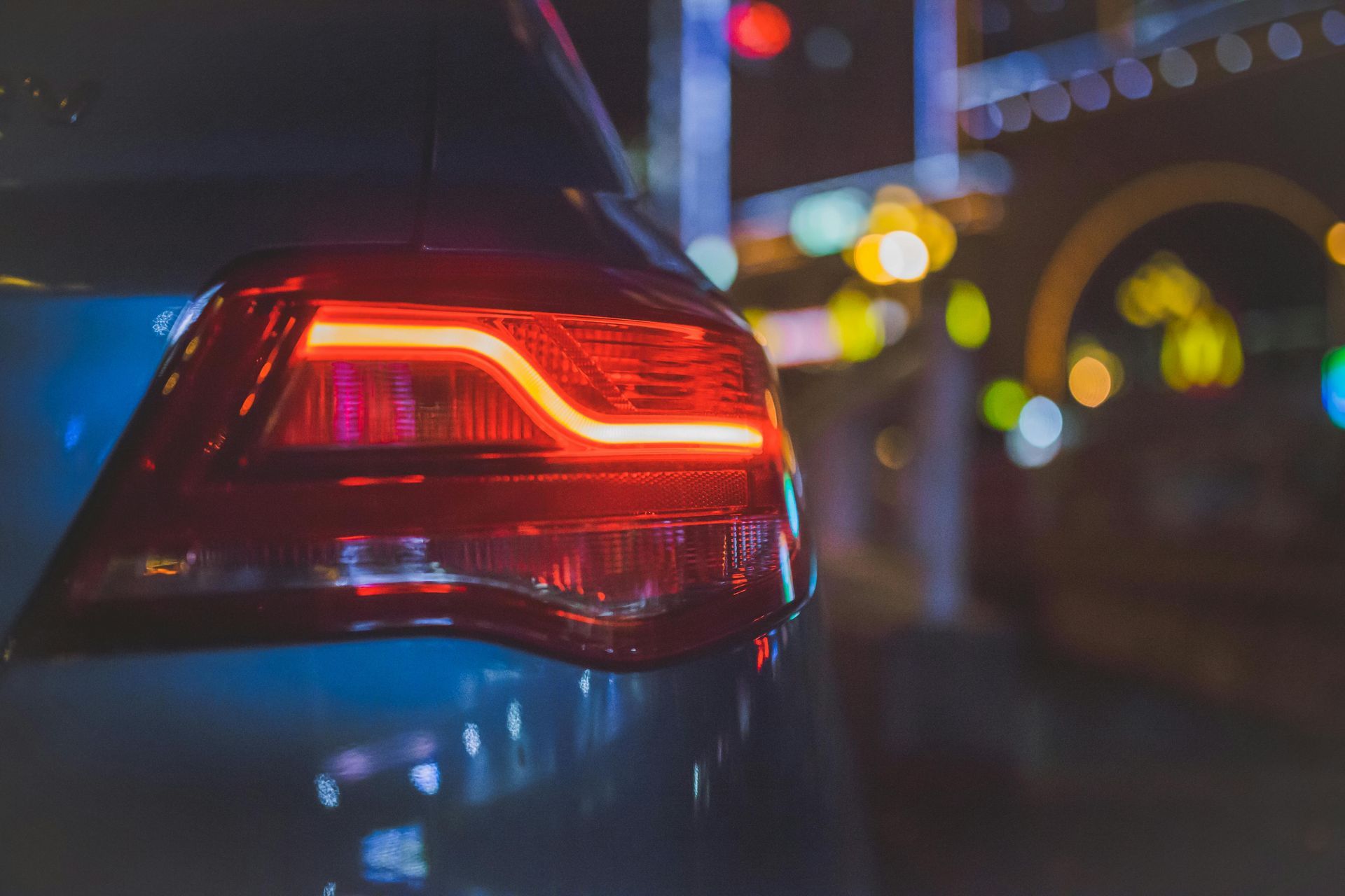 Das Rücklicht eines blauen Autos leuchtete nachts rot, im Hintergrund waren die verschwommenen Lichter der Stadt zu sehen.