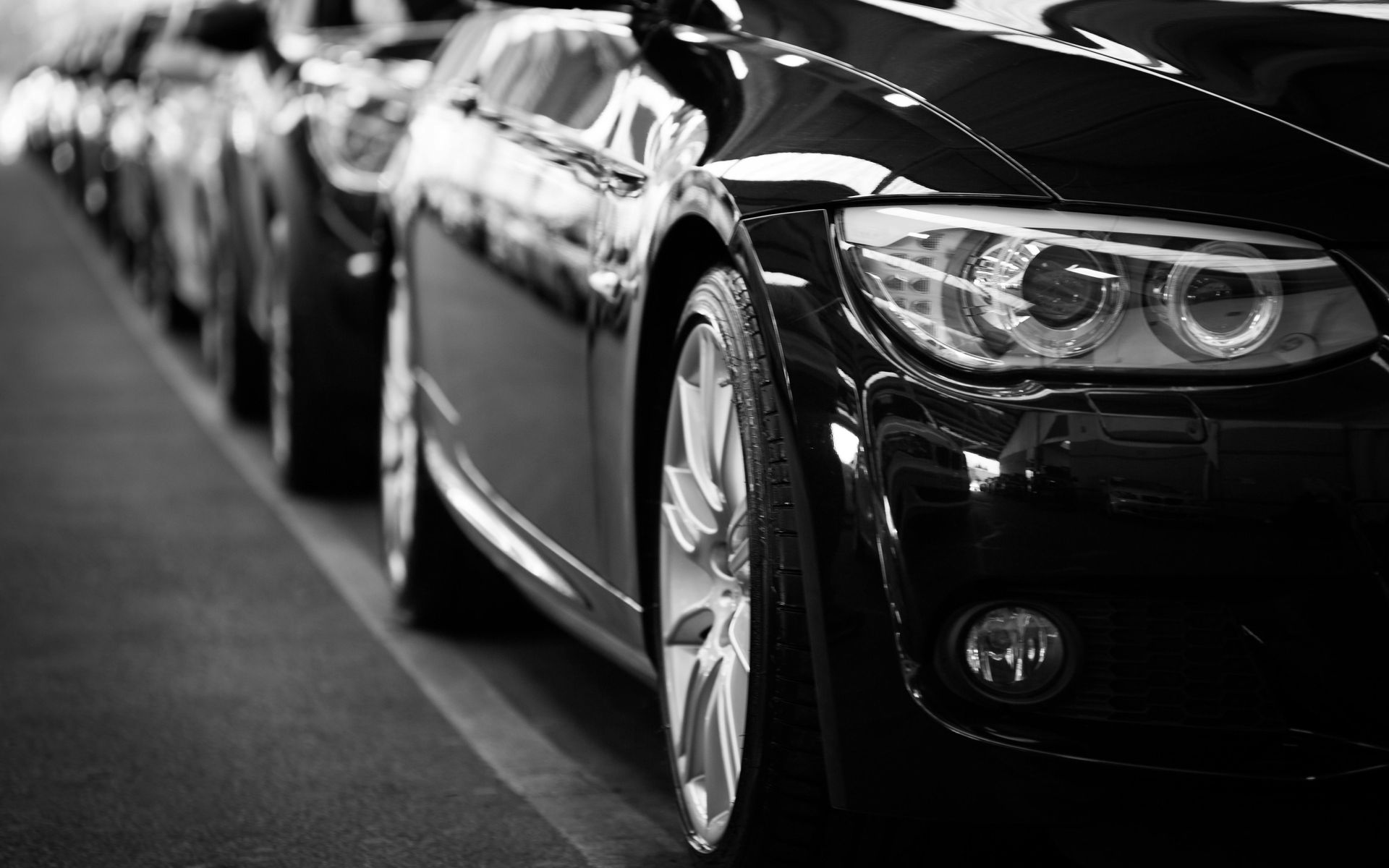 Schwarze Autos reihten sich auf, glänzende Außenlackierung, Fokus der Frontansicht auf den Scheinwerfer.
